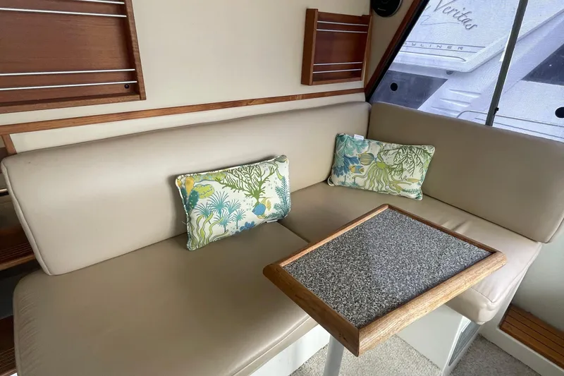 Slide: The Image of 1989 Bayliner Pilothouse 4588 interior with beige seating, decorative pillows, and a small table. - 25