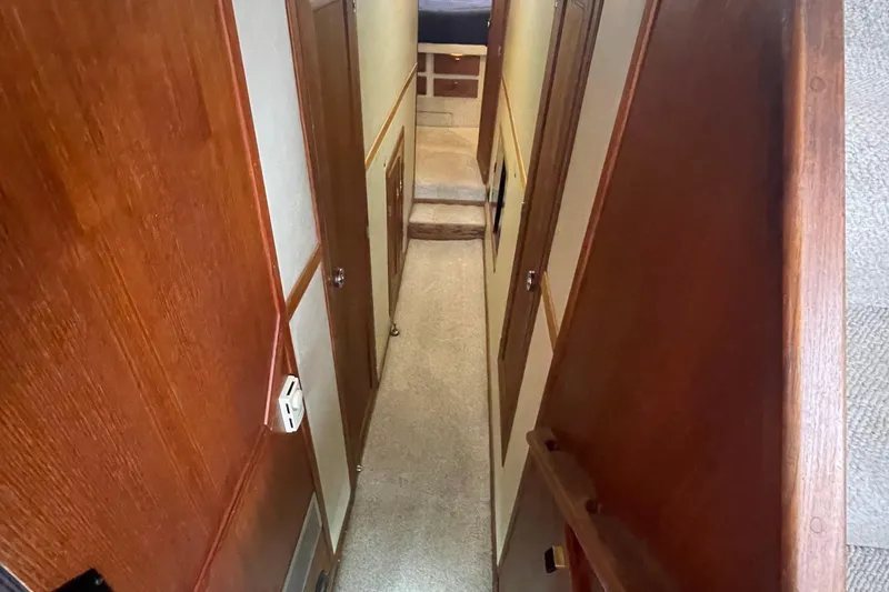 Slide: The Image of Narrow hallway inside 1989 Bayliner Pilothouse 4588, featuring wooden paneling and carpeted floor. - 31