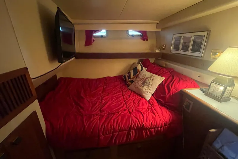 Slide: The Image of Cozy bedroom in 1989 Bayliner Pilothouse 4588 with red bedding and nautical decor. - 32