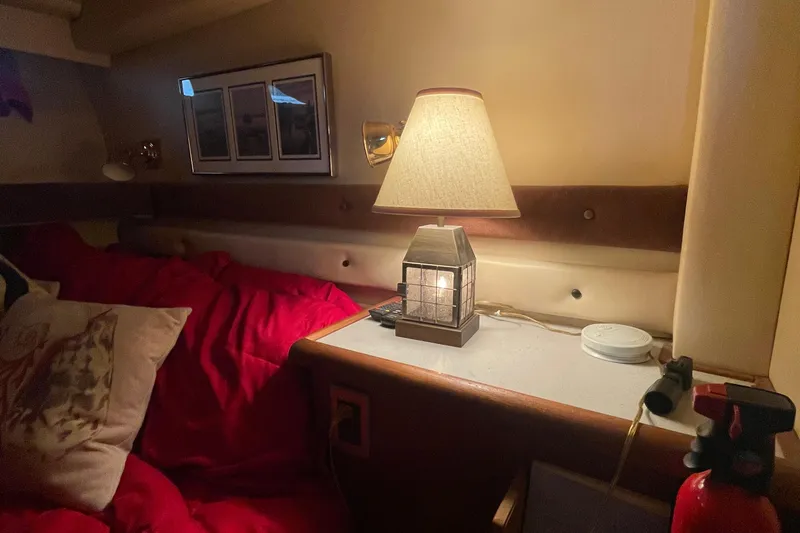 Slide: The Image of Cozy cabin interior of 1989 Bayliner Pilothouse 4588 with lamp and red bedding. - 34