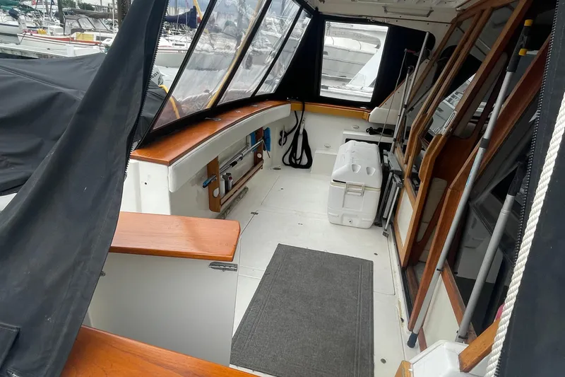 Slide: The Image of 1989 Bayliner Pilothouse 4588 interior with seating, cooler, and wooden accents. - 4