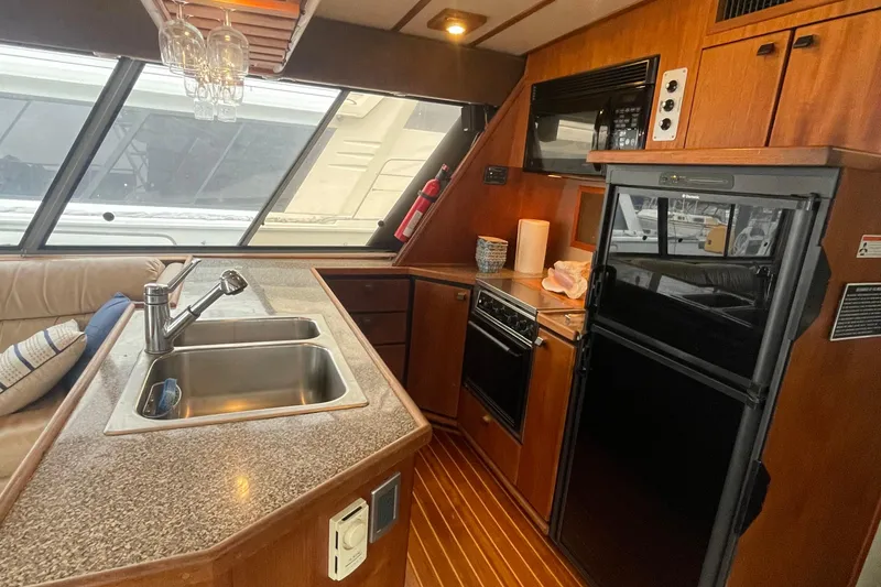 Slide: The Image of Interior of 1989 Bayliner Pilothouse 4588, featuring kitchen with sink, stove, and refrigerator. - 9