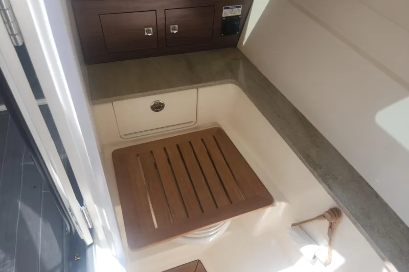 Slide: The Image of 2018 Boston Whaler 320 Vantage interior with wooden seat and storage compartments. - 15