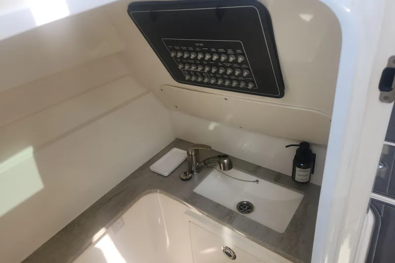Slide: The Image of Interior of 2018 Boston Whaler 320 Vantage boat, featuring a compact sink and control panel. - 16
