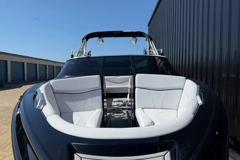 Slide: The Image of 2020 MasterCraft XT25 boat with sleek black exterior and white seating, docked near storage units. - 3