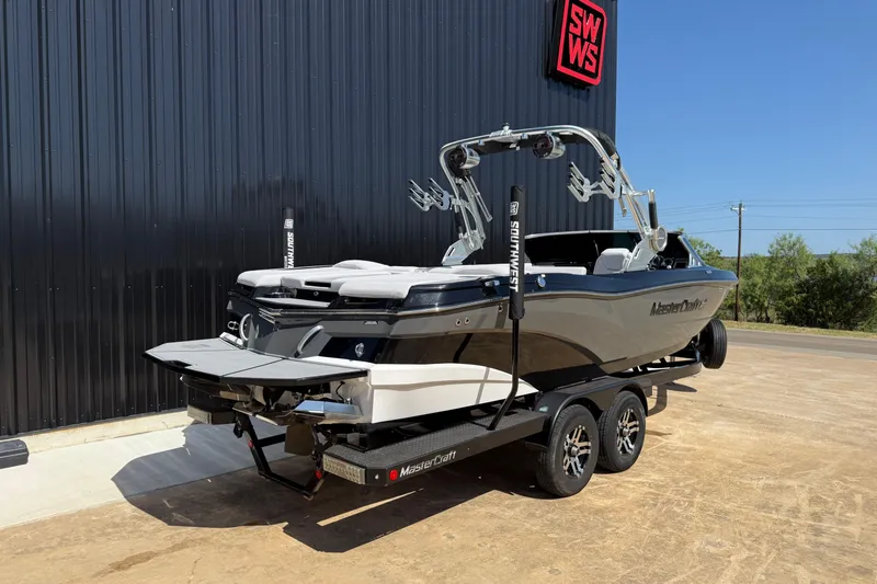 Slide: The Image of 2020 MasterCraft XT25 boat on trailer, parked outdoors near a black building. - 5
