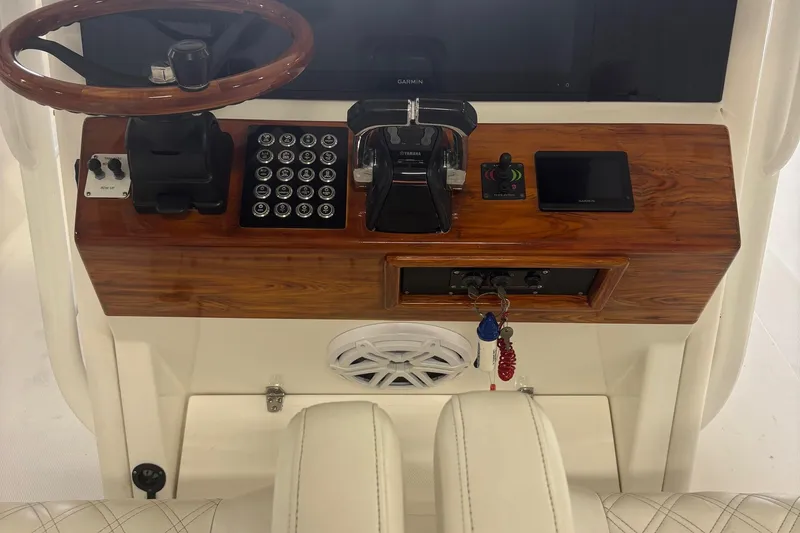 Slide: The Image of Boat dashboard with wooden panel, steering wheel, controls, and Garmin display, Venture 2005 model. - 20