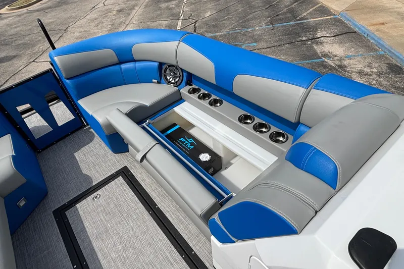 Slide: The Image of 2025 Montara 25 Surf Boss interior with blue and gray seating, cup holders, and storage. - 11