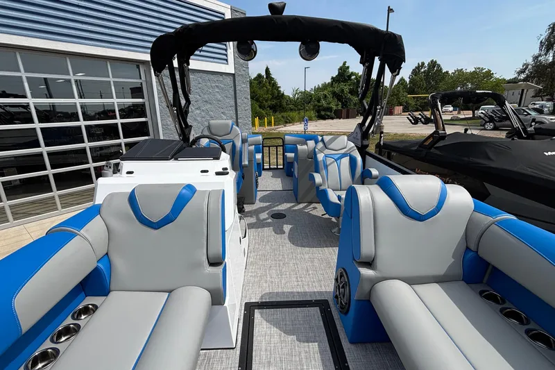 Slide: The Image of 2025 Montara 25 Surf Boss boat interior with blue and gray seating, docked outdoors. - 12