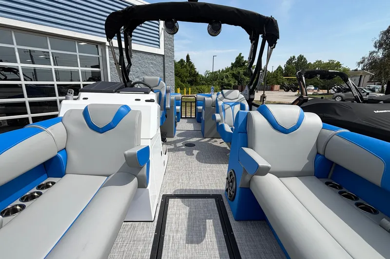 Slide: The Image of 2025 Montara 25 Surf Boss boat interior with blue and gray seating, docked outdoors. - 14
