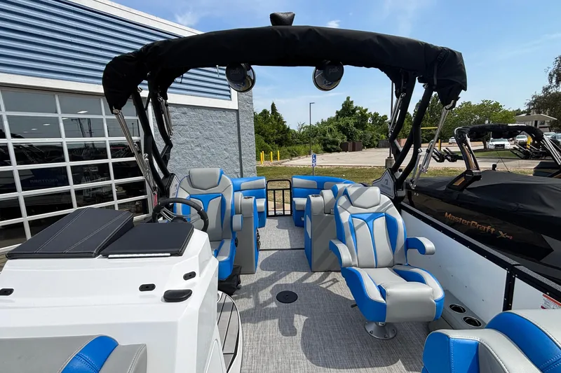 Slide: The Image of 2025 Montara 25 Surf Boss boat interior with blue and gray seating, docked near a building. - 23