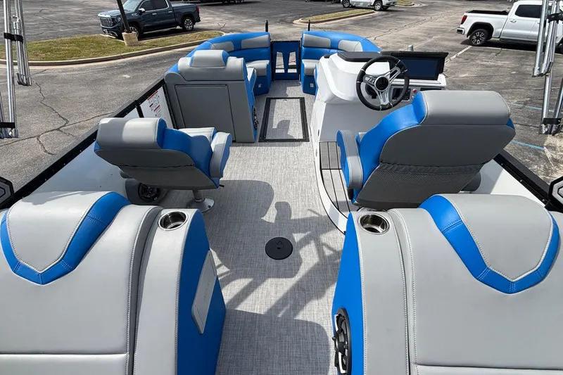 Slide: The Image of 2025 Montara 25 Surf Boss boat interior with blue and gray seating, steering wheel, and cup holders. - 24