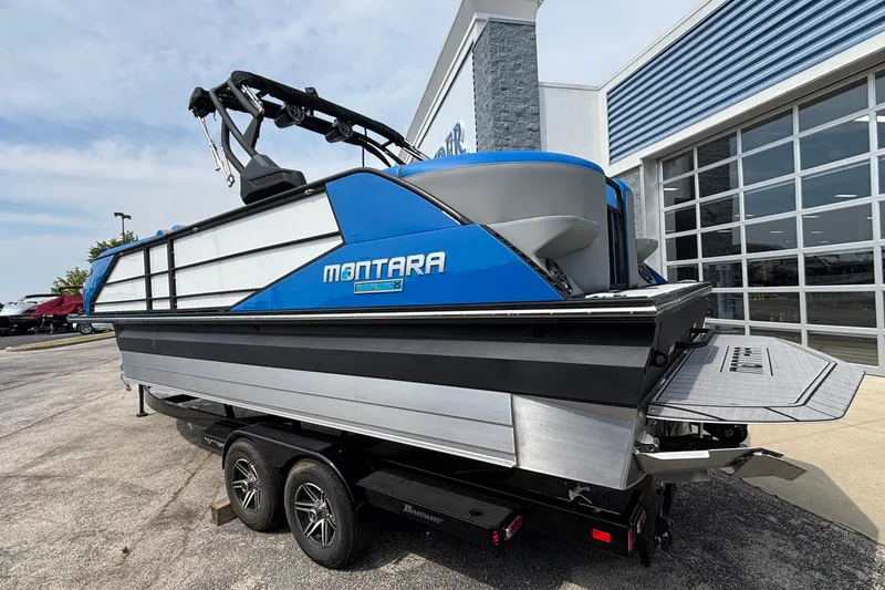Slide: The Image of 2025 Montara 25 Surf Boss boat, blue and silver, displayed outside a showroom. - 5