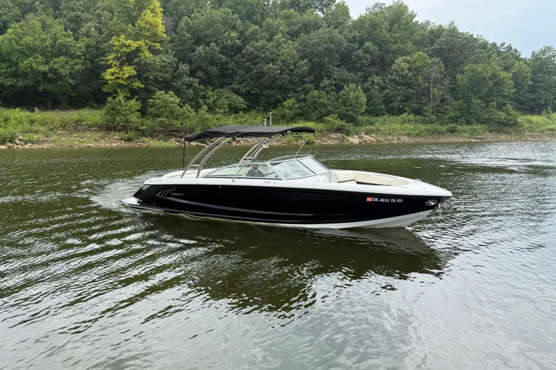 Slide: The Image of 2013 Cobalt A28 boat cruising on a calm lake with lush green forest backdrop. - 13