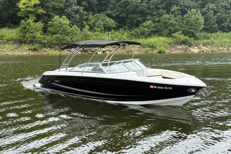 Slide: The Image of 2013 Cobalt A28 boat cruising on a scenic river with lush green trees. - 14