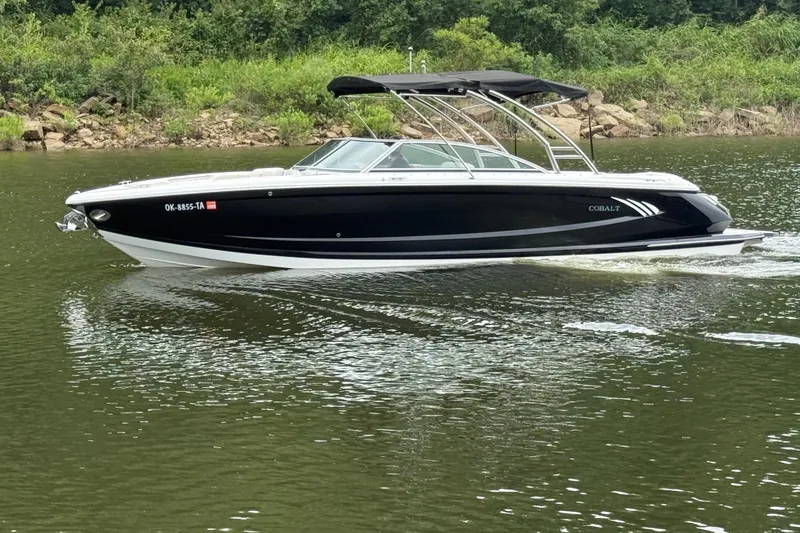 Slide: The Image of 2013 Cobalt A28 boat cruising on a lake with lush green shoreline. - 18