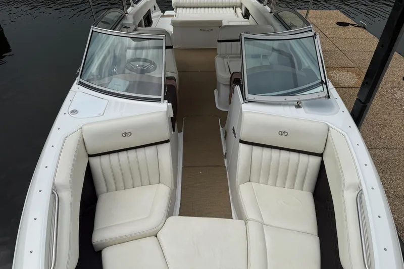 Slide: The Image of 2013 Cobalt A28 boat with white leather seating and dual windshields, docked by the water. - 23