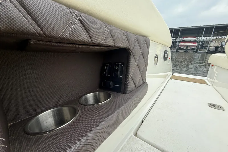 Slide: The Image of 2013 Cobalt A28 boat interior with cup holders and control panel, docked by the water. - 36