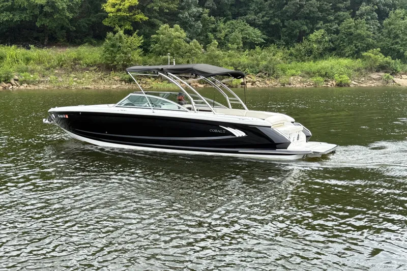 Slide: The Image of 2013 Cobalt A28 boat cruising on a calm river with lush green shoreline. - 7