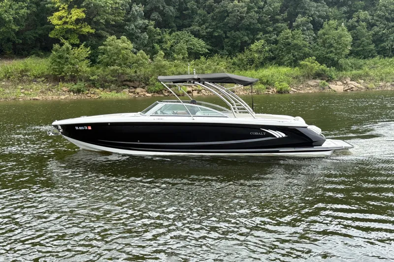 Slide: The Image of 2013 Cobalt A28 boat cruising on a scenic river with lush green shoreline. - 8