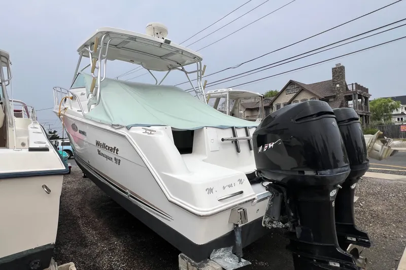Slide: The Image of 2001 Wellcraft 290 Coastal boat with twin outboard engines, docked on gravel. - 6