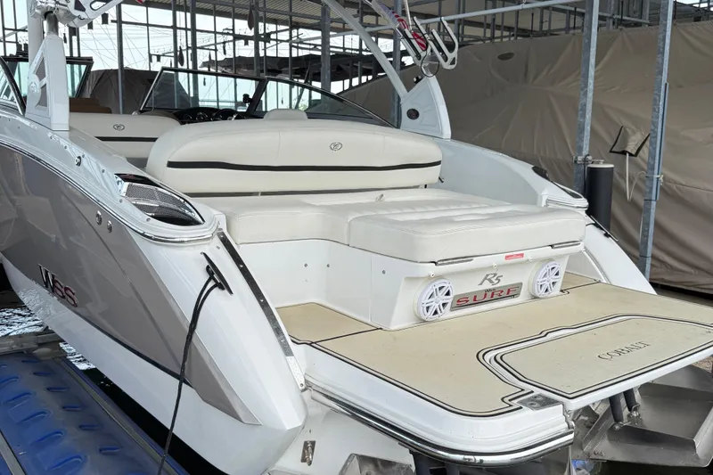 Slide: The Image of 2016 Cobalt R5 WSS Surf boat with spacious seating and sleek design in a marina. - 2