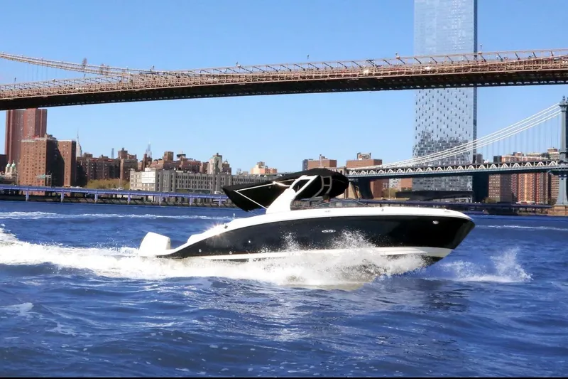 Slide: The Image of 2020 Sea Ray boat cruising under iconic city bridges on a sunny day. - 2