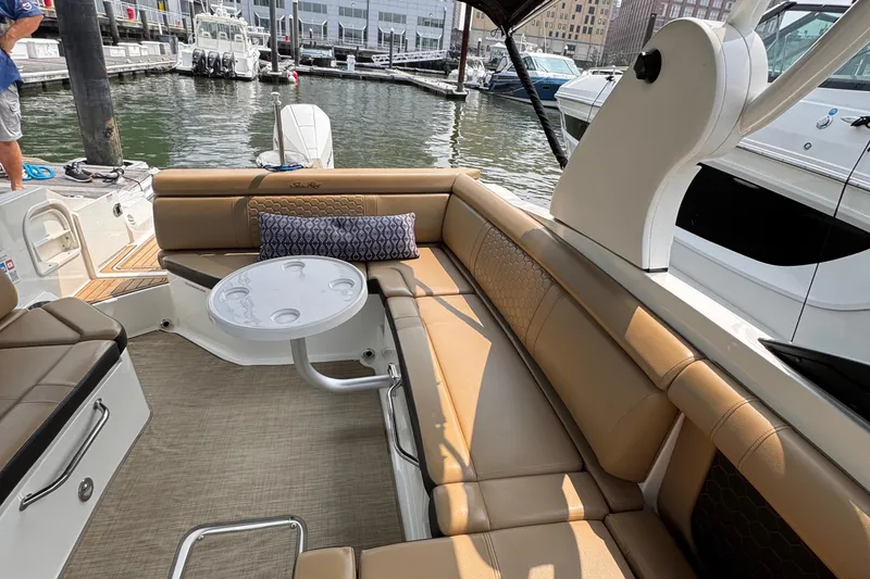 Slide: The Image of Luxurious 2020 Sea Ray boat interior with tan seating and a small table at a marina. - 25