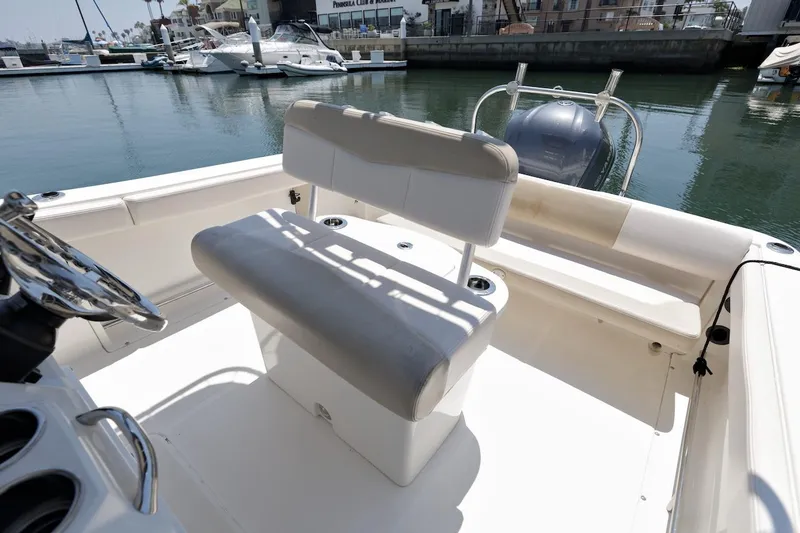 Slide: The Image of 2016 Robalo R222 Center Console boat interior with seating and steering wheel, docked at marina. - 10