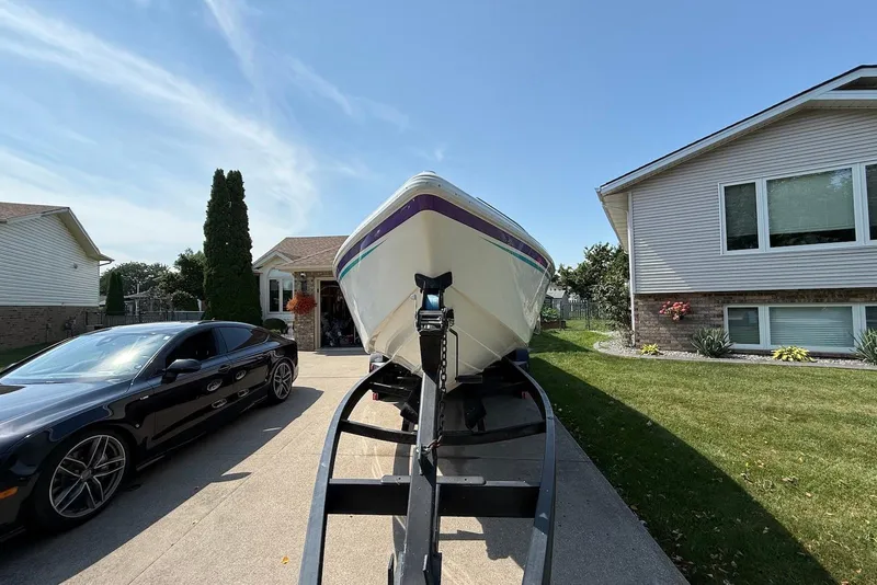 Slide: The Image of 1995 Checkmate Persuader 261 boat on trailer beside a black car in driveway. - 12