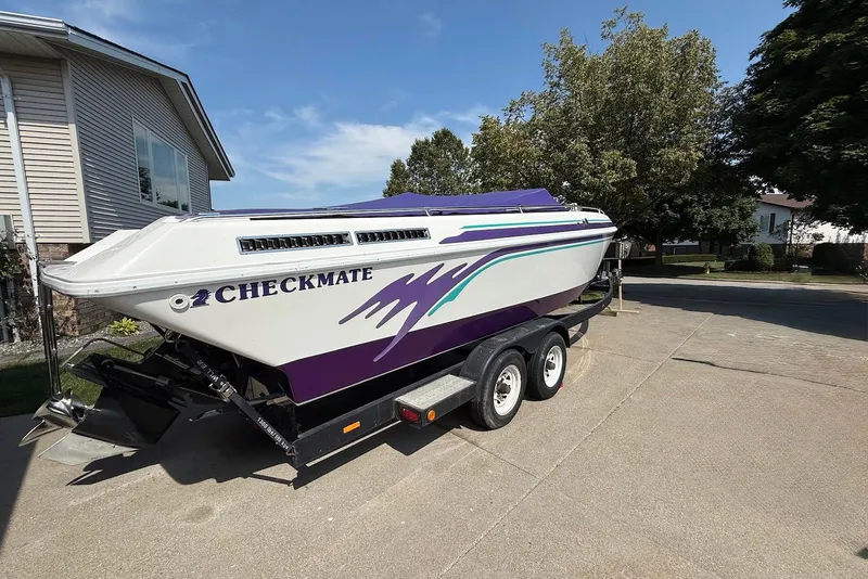 Slide: The Image of 1995 Checkmate Persuader 261 boat on trailer, white with purple accents, parked in driveway. - 14