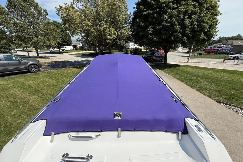 Slide: The Image of 1995 Checkmate Persuader 261 boat with purple cover, parked on a residential street. - 24