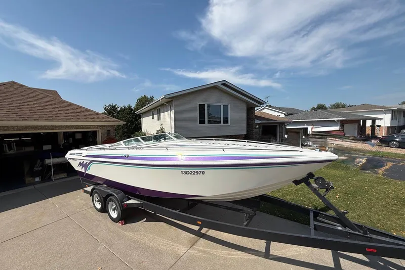 Slide: The Image of 1995 Checkmate Persuader 261 boat on trailer, parked in suburban driveway under clear sky. - 44