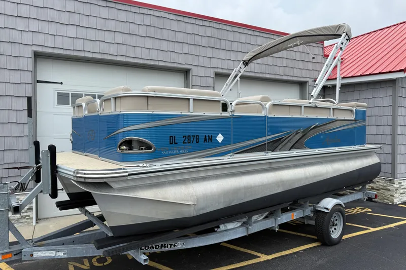 Slide: The Image of 2020 Avalon Venture Cruise 18' pontoon boat on trailer, parked outside a building. - 2
