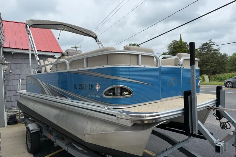 Slide: The Image of 2020 Avalon Venture Cruise 18' pontoon boat on trailer, blue exterior, parked near building. - 3