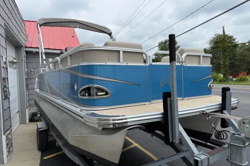 Slide: The Image of 2020 Avalon Venture Cruise 18' pontoon boat on trailer, blue exterior, parked outdoors. - 4