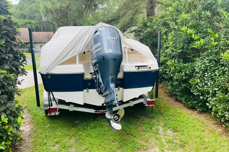 Slide: The Image of 2019 Robalo R207 Dual Console boat with Yamaha engine, covered and parked on grass. - 11