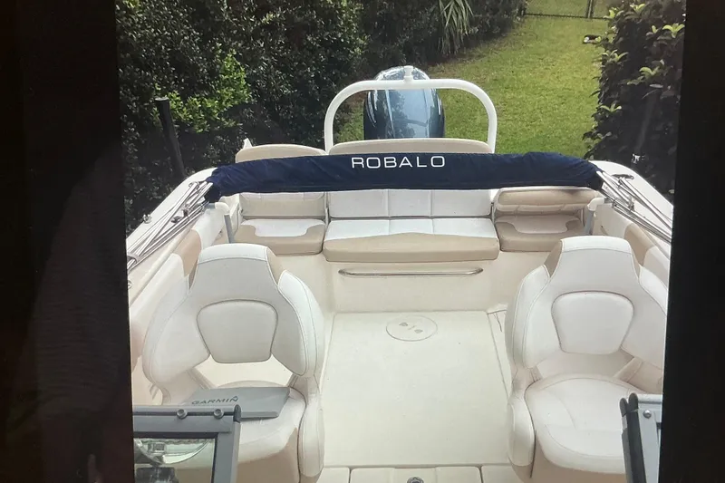Slide: The Image of 2019 Robalo R207 Dual Console boat interior with seating and lush greenery background. - 15