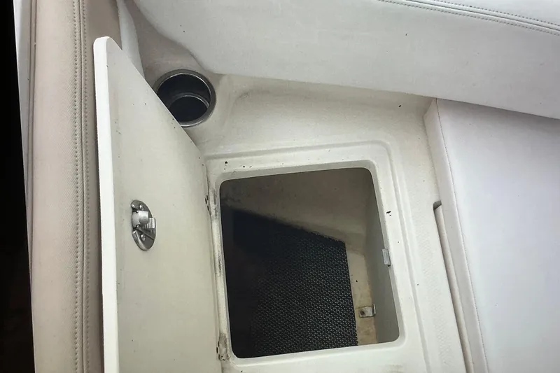 Slide: The Image of 2019 Robalo R207 Dual Console storage compartment with open hatch and cup holder. - 17