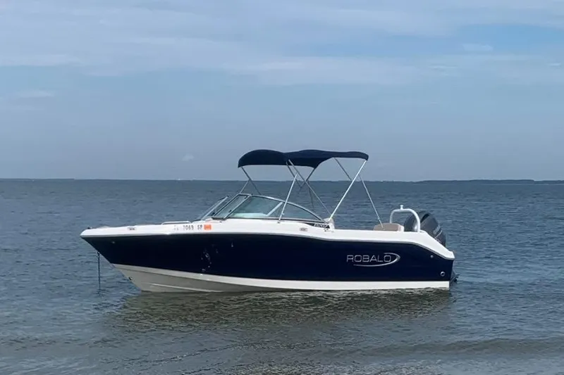 Slide: The Image of 2019 Robalo R207 Dual Console boat floating on calm water. - 2