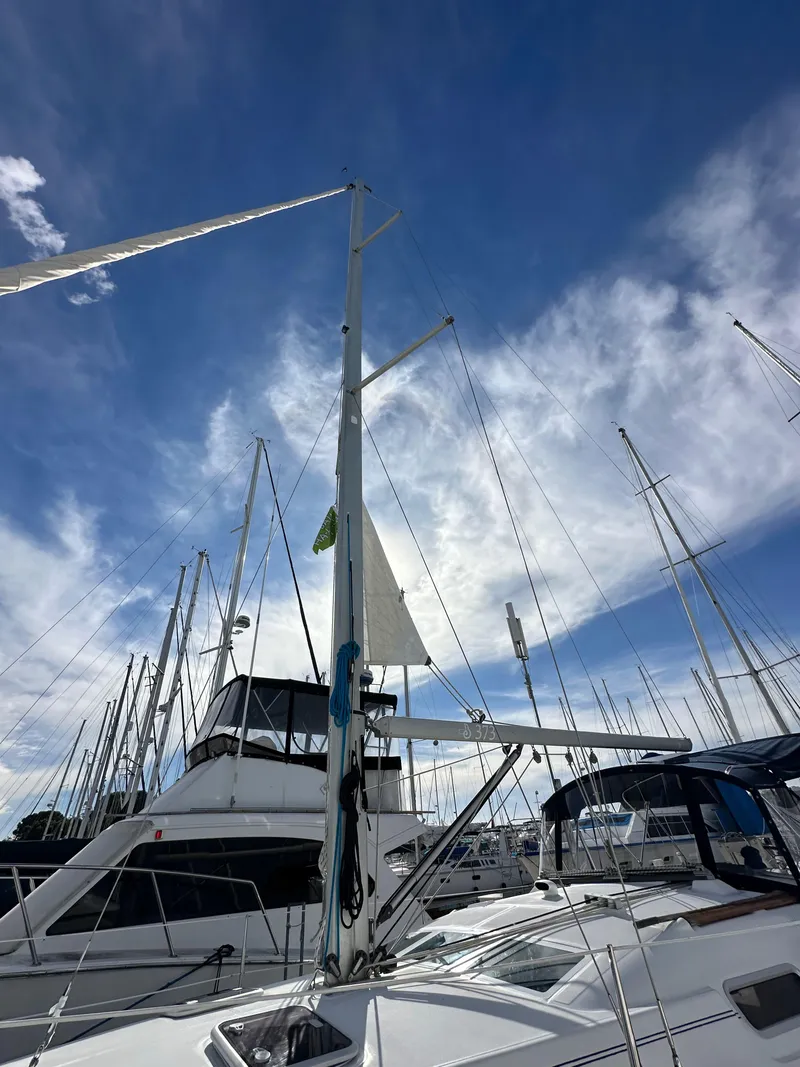 Slide: The Image of 2005 Beneteau 373 sailboat docked under a vibrant blue sky with clouds. - 2