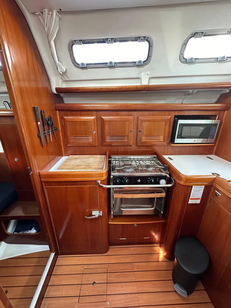 Slide: The Image of 2005 Beneteau 373 yacht kitchen with wood cabinetry, stove, and microwave. - 31