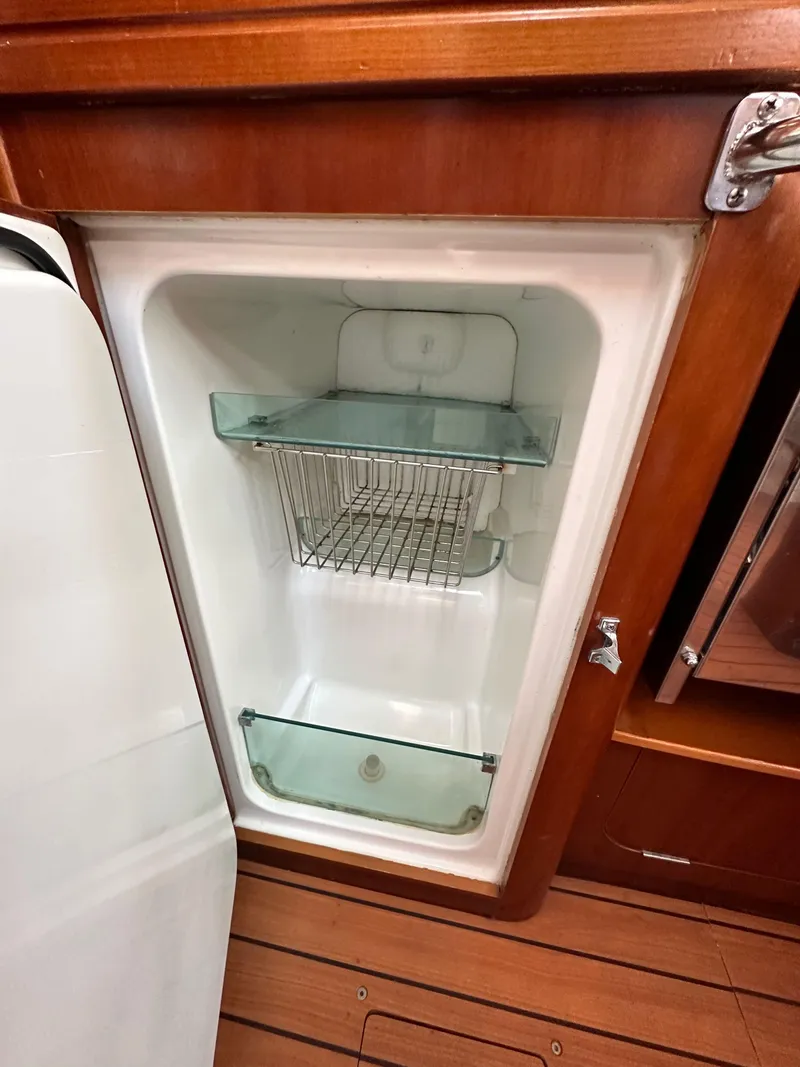 Slide: The Image of 2005 Beneteau 373 yacht refrigerator with wooden trim and wire shelf. - 32