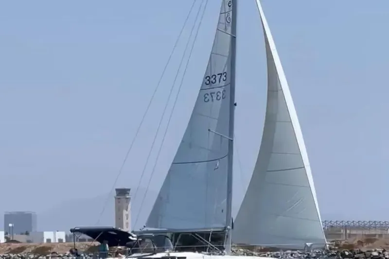 Slide: The Image of 2005 Beneteau 373 sailboat with sails up, cruising near a coastal area. - 73