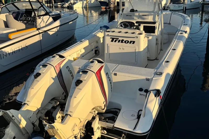 Slide: The Image of 2003 Triton 2690 CC boat with dual Evinrude engines docked at marina. - 2