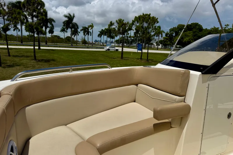 Slide: The Image of 2023 Scout 215 Dorado boat interior with beige seating, palm trees in background. - 10