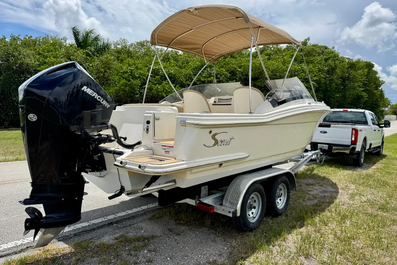 Slide: The Image of 2023 Scout 215 Dorado boat on trailer, featuring Mercury outboard motor, parked roadside. - 4