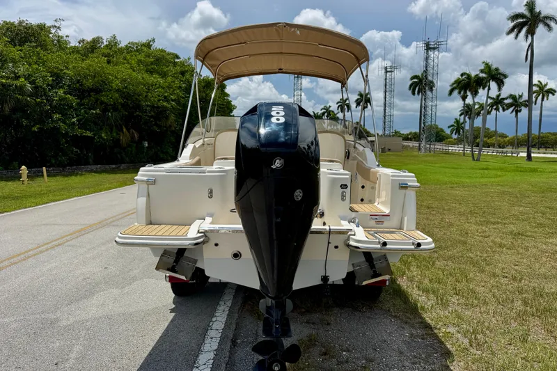 Slide: The Image of 2023 Scout 215 Dorado boat with outboard motor, parked on a road near palm trees. - 5
