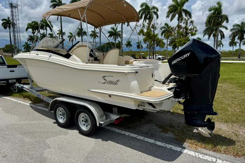 Slide: The Image of 2023 Scout 215 Dorado boat on trailer with Mercury engine, parked near palm trees. - 6