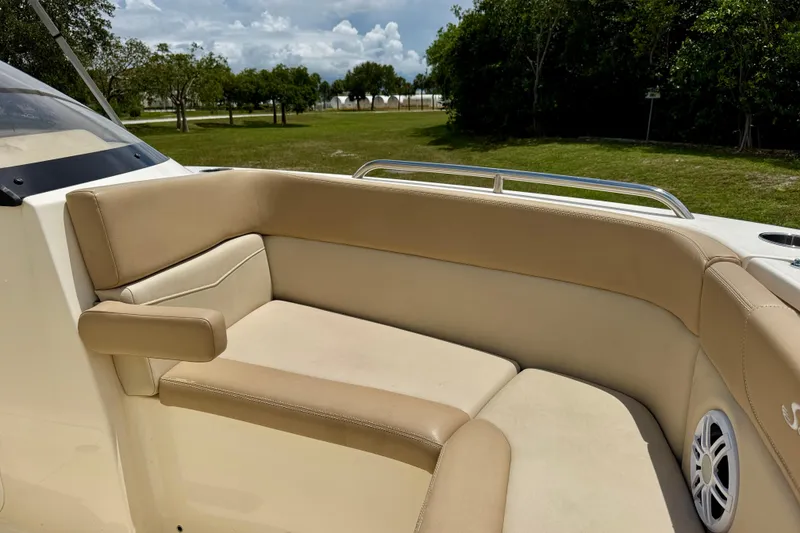 Slide: The Image of 2023 Scout 215 Dorado boat interior with beige seating and speaker, surrounded by greenery. - 9